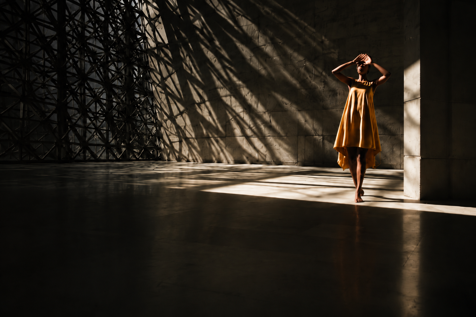 A woman in a gold dress standing in a vast concrete hall crossed by lattice shadows